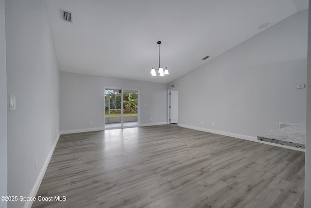 empty room featuring lofted ceiling, an inviting chandelier, and light hardwood / wood-style flooring