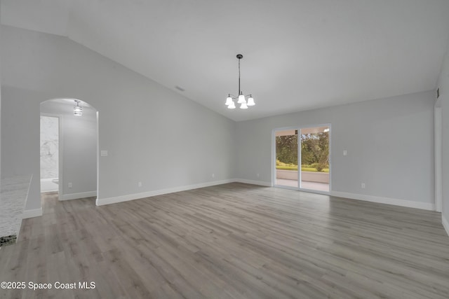 unfurnished room with lofted ceiling, light hardwood / wood-style floors, and a chandelier