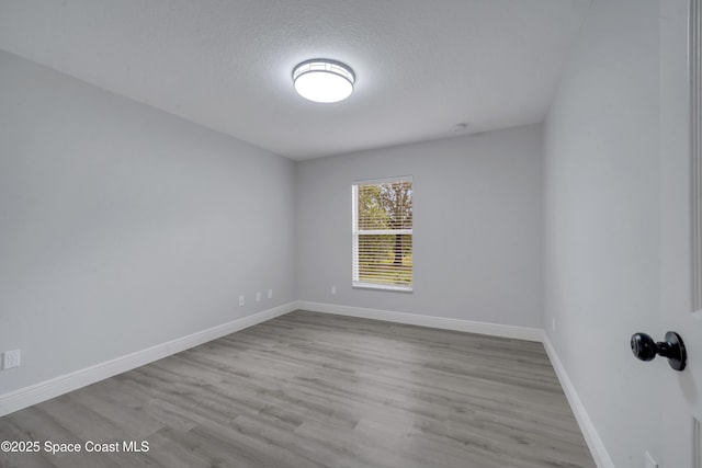 empty room with a textured ceiling and light hardwood / wood-style flooring