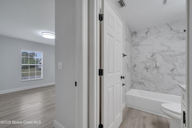 full bathroom featuring toilet, a textured ceiling, vanity, tiled shower / bath combo, and hardwood / wood-style floors