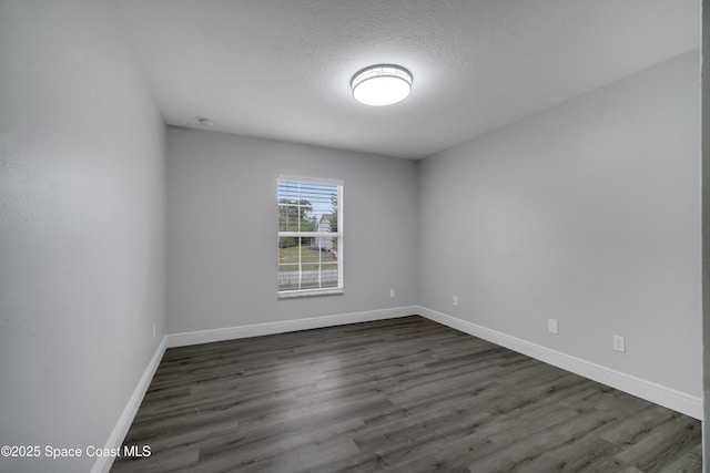 empty room featuring dark wood-type flooring and a textured ceiling