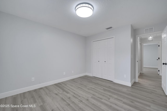 unfurnished bedroom featuring light hardwood / wood-style flooring, a closet, and a textured ceiling