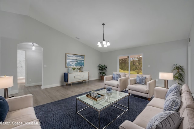 1064 Tevis St SE, Palm Bay, FL 32909 - living room with arched walkways, a chandelier, wood finished floors, baseboards, and high vaulted ceiling