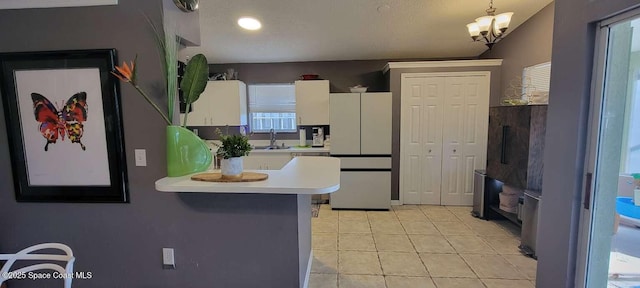 kitchen with sink, white cabinetry, white refrigerator, a kitchen bar, and decorative light fixtures