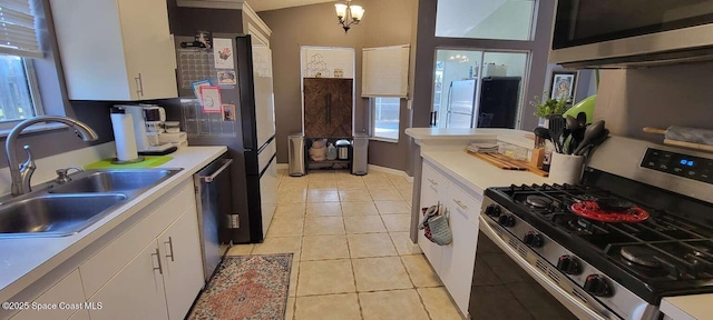 kitchen with sink, white cabinetry, hanging light fixtures, light tile patterned floors, and appliances with stainless steel finishes