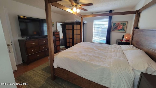 bedroom with a textured ceiling, dark hardwood / wood-style floors, and ceiling fan