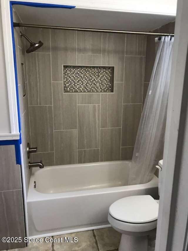 bathroom featuring tile patterned floors, toilet, and shower / bath combo with shower curtain