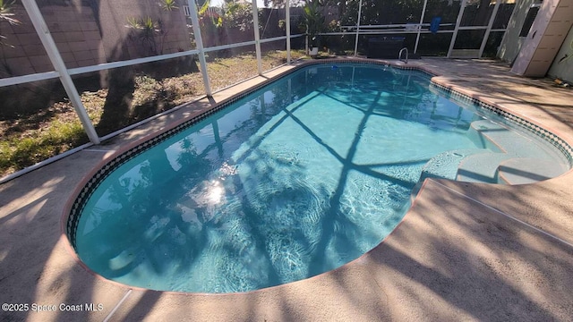 view of pool with a patio and glass enclosure