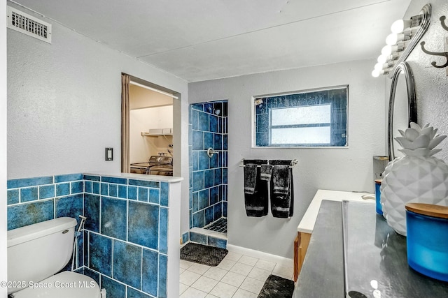 bathroom featuring vanity, tile patterned floors, toilet, and a tile shower