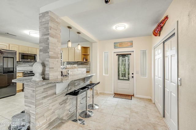 kitchen with hanging light fixtures, stainless steel appliances, a kitchen breakfast bar, tasteful backsplash, and light stone countertops