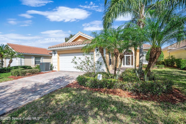 mediterranean / spanish home featuring a garage, central AC, and a front lawn