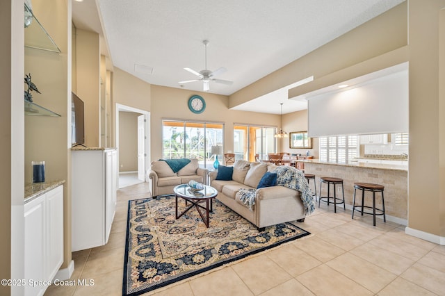 living room featuring light tile patterned floors, a textured ceiling, and ceiling fan