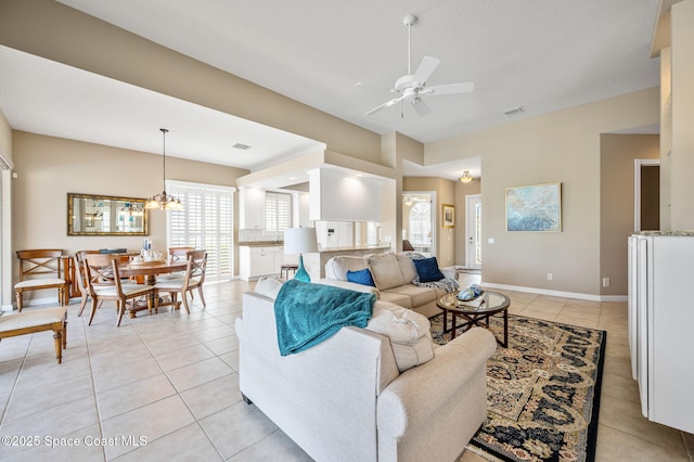 living room featuring light tile patterned flooring and ceiling fan with notable chandelier