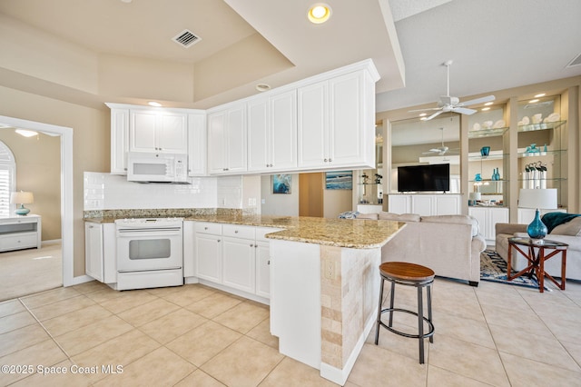 kitchen featuring light tile patterned floors, white cabinets, white appliances, and kitchen peninsula