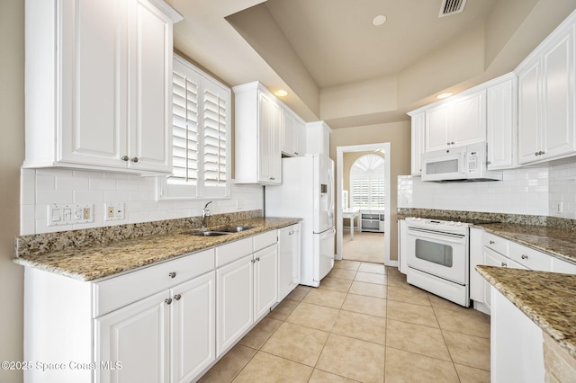 kitchen with light tile patterned flooring, sink, stone counters, white appliances, and white cabinets