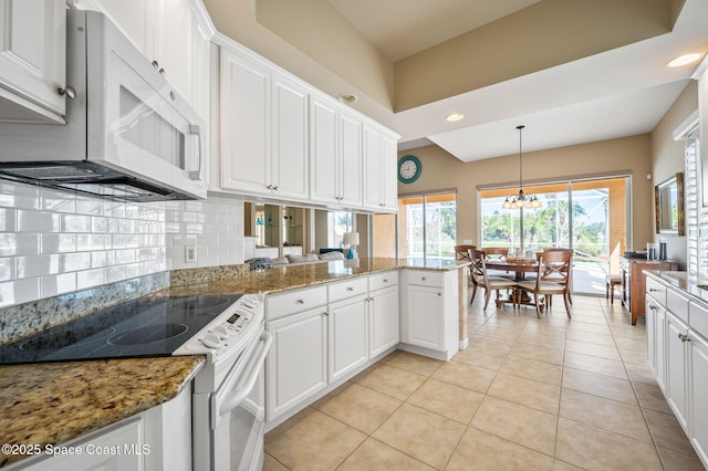 kitchen with white appliances, tasteful backsplash, white cabinets, decorative light fixtures, and kitchen peninsula