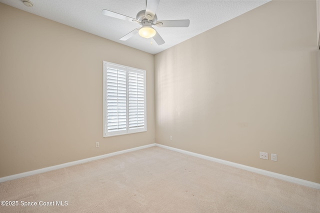 empty room with ceiling fan, light colored carpet, and a textured ceiling