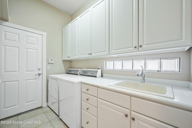 laundry area with sink, light tile patterned floors, cabinets, a wealth of natural light, and separate washer and dryer