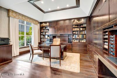 home office featuring crown molding, lofted ceiling, dark hardwood / wood-style floors, and built in shelves