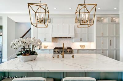 kitchen with an inviting chandelier, hanging light fixtures, light stone counters, and a kitchen bar