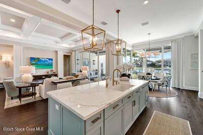 kitchen with coffered ceiling, sink, an island with sink, and decorative light fixtures