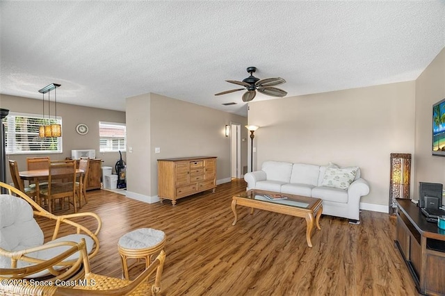 living room with ceiling fan, dark hardwood / wood-style flooring, and a textured ceiling