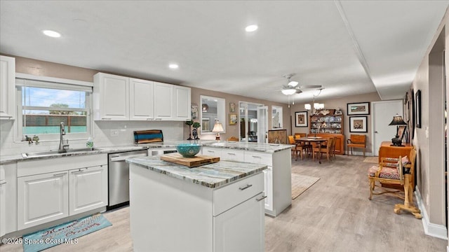 kitchen featuring sink, light hardwood / wood-style flooring, a center island, white cabinets, and stainless steel dishwasher