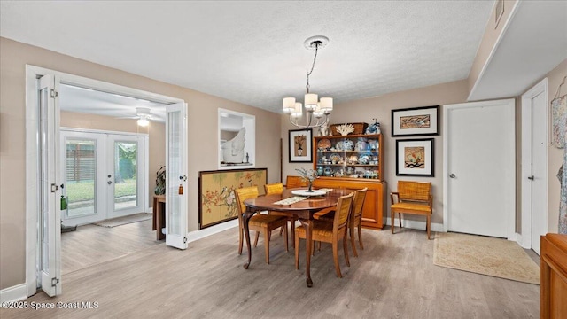 dining room with french doors, a notable chandelier, a textured ceiling, and light wood-type flooring