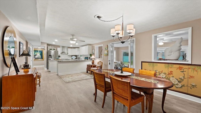 dining area with an inviting chandelier, light hardwood / wood-style floors, and a textured ceiling