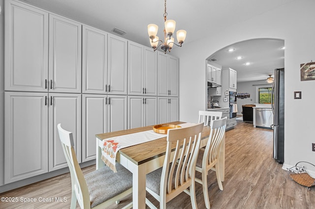 dining space with light hardwood / wood-style floors and ceiling fan with notable chandelier