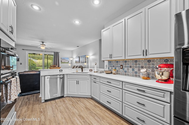 kitchen with sink, light hardwood / wood-style flooring, white cabinetry, stainless steel appliances, and tasteful backsplash