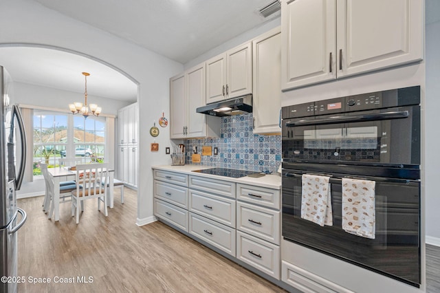 kitchen featuring light hardwood / wood-style flooring, black appliances, white cabinets, decorative light fixtures, and a chandelier