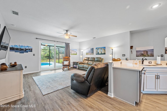 living room featuring sink, light hardwood / wood-style floors, and ceiling fan