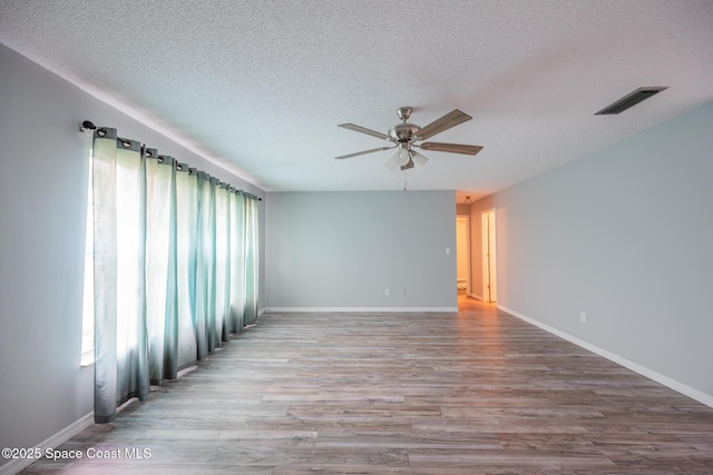 empty room featuring ceiling fan, light hardwood / wood-style flooring, and a textured ceiling