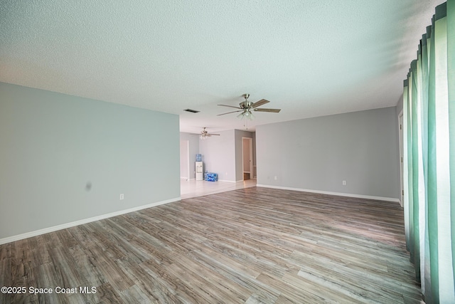 unfurnished living room with ceiling fan, a textured ceiling, and light hardwood / wood-style flooring