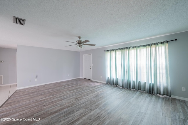 empty room with hardwood / wood-style flooring, ceiling fan, and a textured ceiling