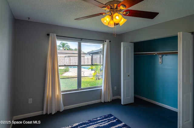 unfurnished bedroom with concrete flooring, a textured ceiling, ceiling fan, and a closet