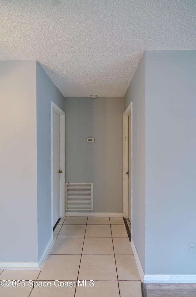 hallway featuring a textured ceiling and light tile patterned floors