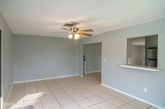 tiled spare room with sink, a textured ceiling, and ceiling fan