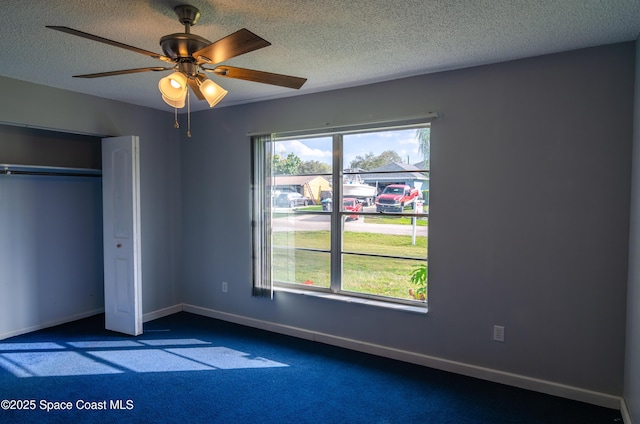 unfurnished bedroom with a textured ceiling, carpet floors, a closet, and ceiling fan