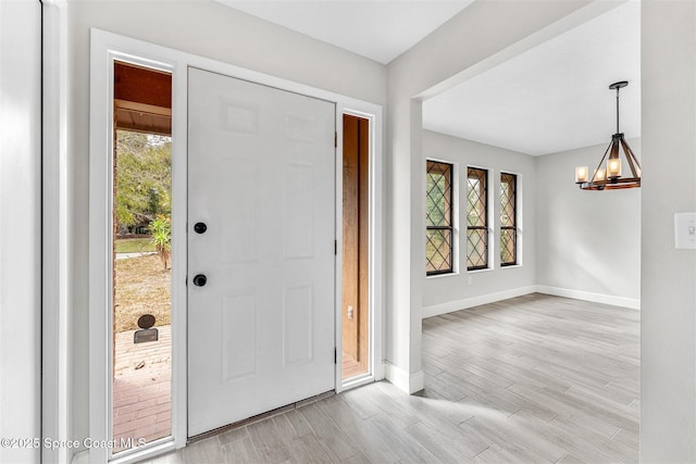 foyer with a healthy amount of sunlight, a chandelier, and light hardwood / wood-style floors