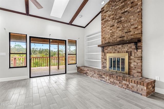 unfurnished living room featuring a skylight, beam ceiling, a fireplace, and high vaulted ceiling