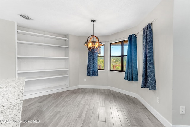 unfurnished dining area with an inviting chandelier and wood-type flooring