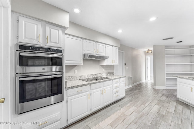 kitchen with stainless steel double oven, black electric stovetop, light stone countertops, and white cabinets