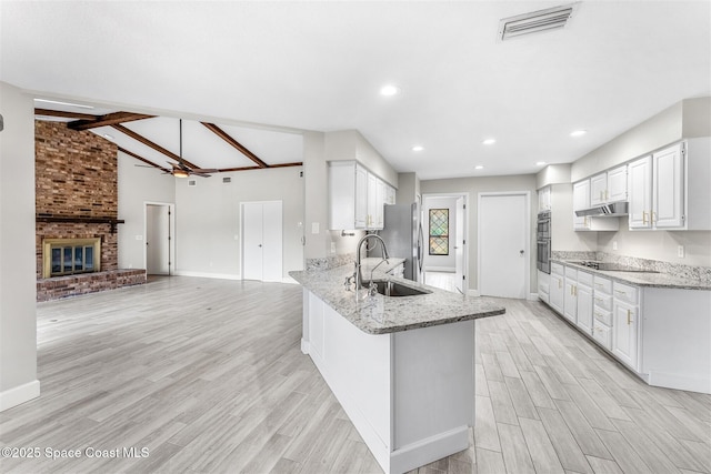 kitchen with white cabinetry, vaulted ceiling with beams, sink, kitchen peninsula, and light stone countertops