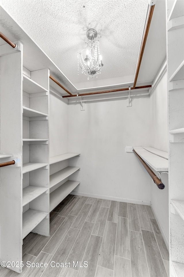 walk in closet with light hardwood / wood-style floors and a chandelier