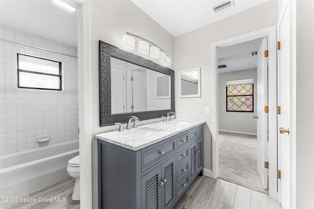 full bathroom with vanity, tiled shower / bath combo, and toilet