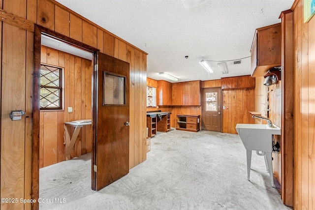 kitchen with wooden walls, light colored carpet, and a textured ceiling