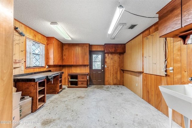 interior space with sink, wooden walls, and a textured ceiling