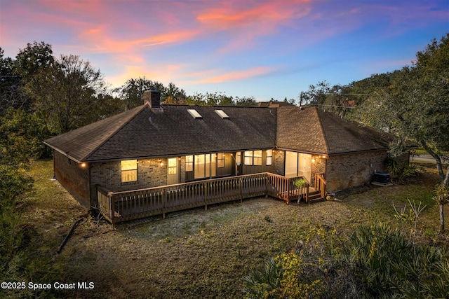 back house at dusk with central AC unit and a deck